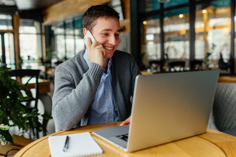 Smiling young man working on his laptop from a cafe