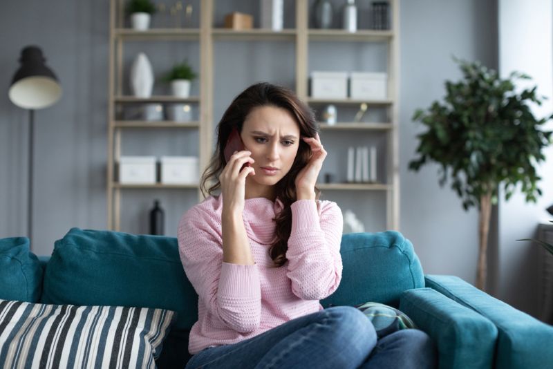 Concerned woman on a phone call from living room