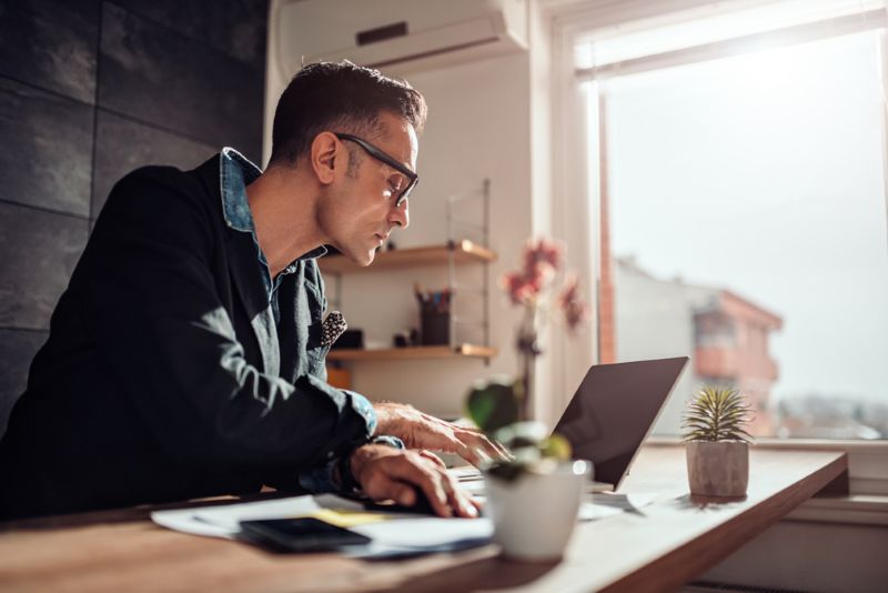 Man in his kitchen researching on his laptop Swift 1